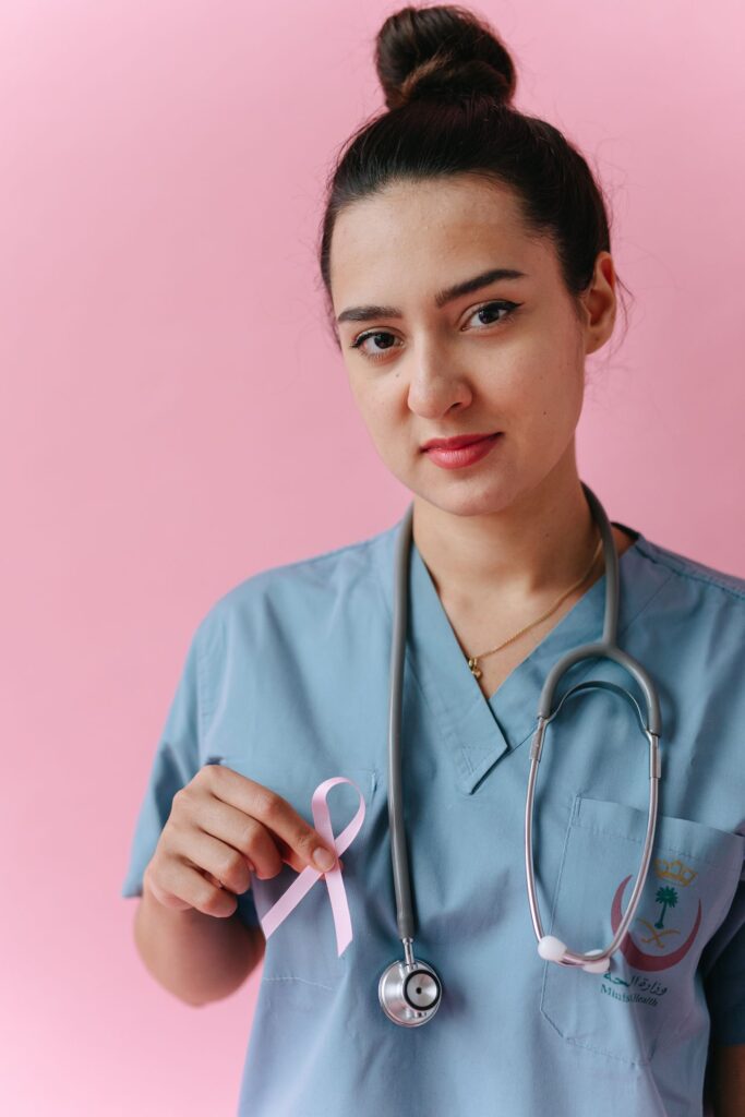 Female doctor in scrubs with pink ribbon for breast cancer awareness
