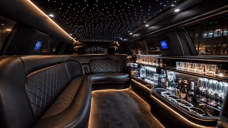 image - Lead Grow Develop - Business, Technology, Personal Development Luxurious limousine interior with black quilted leather seating, a back bar with glassware, and a starry ceiling lighting.