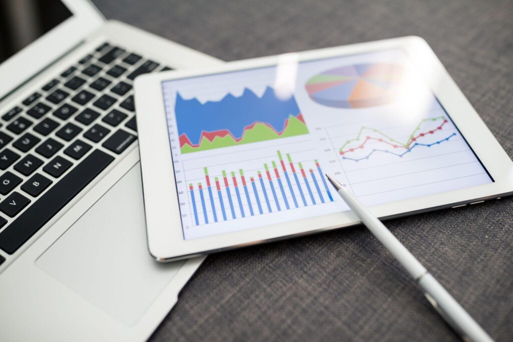 image - Lead Grow Develop - Business, Technology, Personal Development Tablet displaying colorful charts and graphs next to a laptop keyboard, with a white stylus nearby
