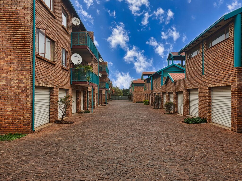 pexels-alexander-f-ungerer-157458816-29007345 - Lead Grow Develop - Business, Technology, Personal Development View of a modern brick apartment complex with garages and balconies under a clear blue sky