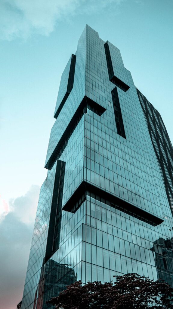 Stunning modern skyscraper with glass panels under a clear blue sky, viewed from below