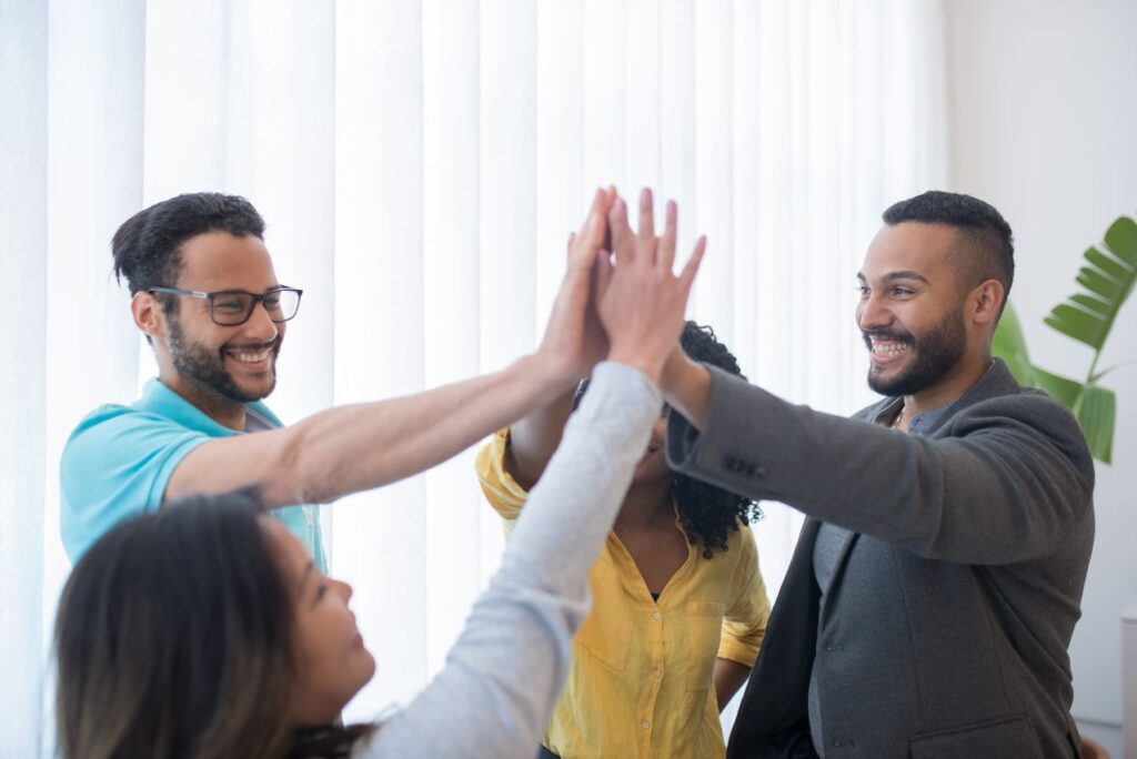pexels-kampus-8204394 - Lead Grow Develop - Business, Technology, Personal Development Happy diverse team in a bright office celebrating success with a high five