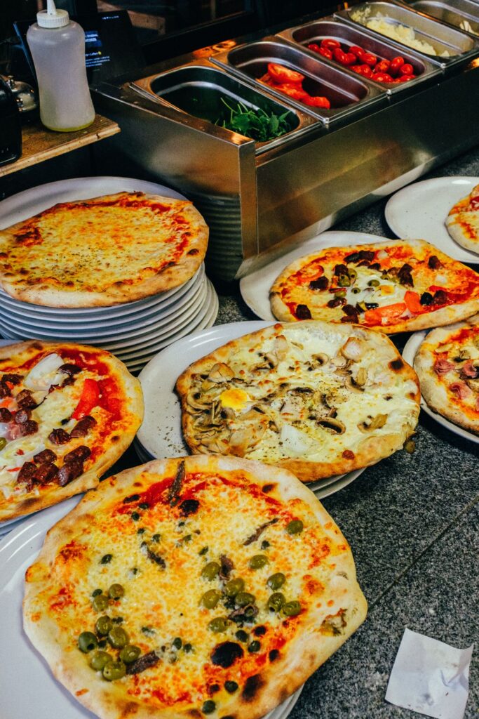 Multiple freshly baked pizzas displayed in a restaurant setting, showcasing assorted toppings