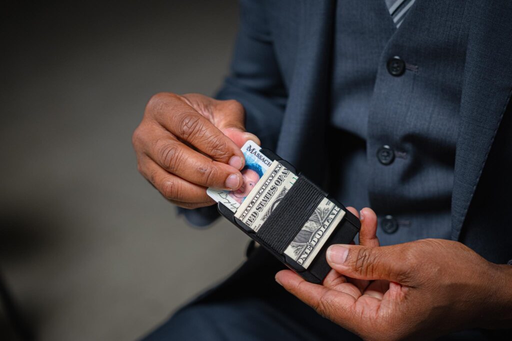 image - Lead Grow Develop - Business, Technology, Personal Development Close-up of a person in a dark suit adjusting a money belt with folded US dollar bills visible in the belt pouch