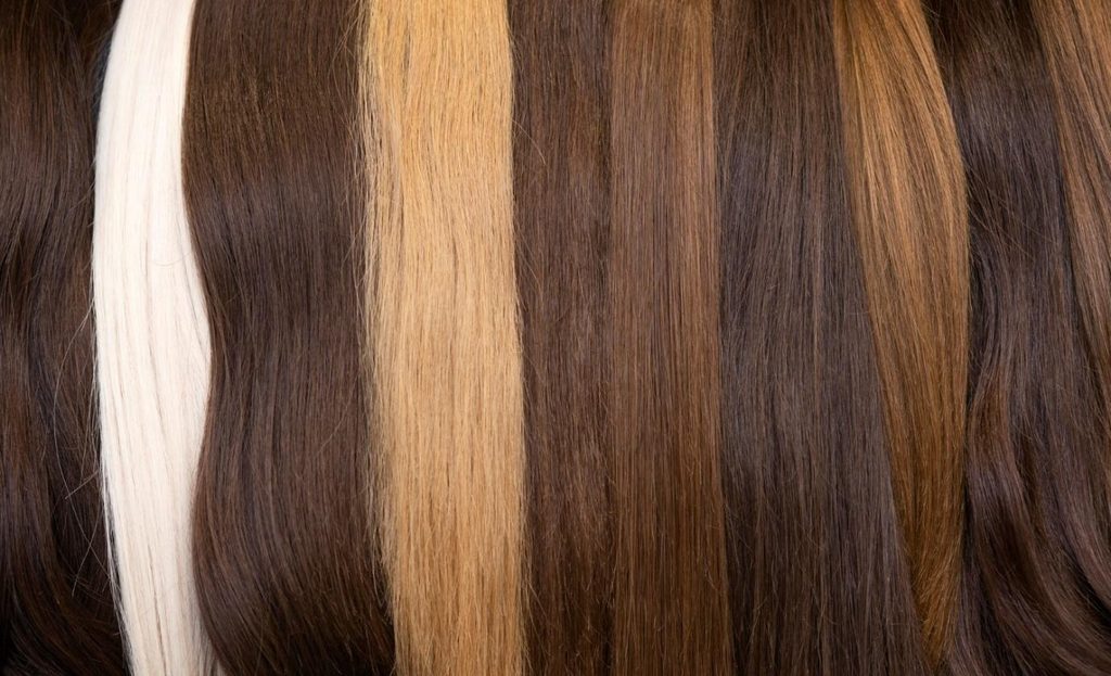 Close-up of layered hair strands in brown, blonde, and white streaks, showing color variation.