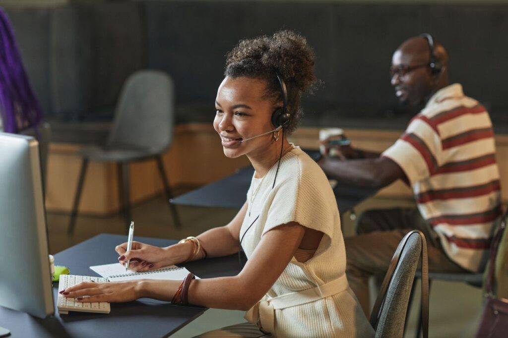 Cheerful woman in a call center using a headset and computer while working