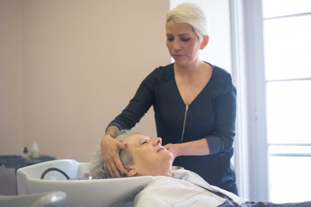 A hairdresser provides a relaxing washing service to an elderly woman in a salon