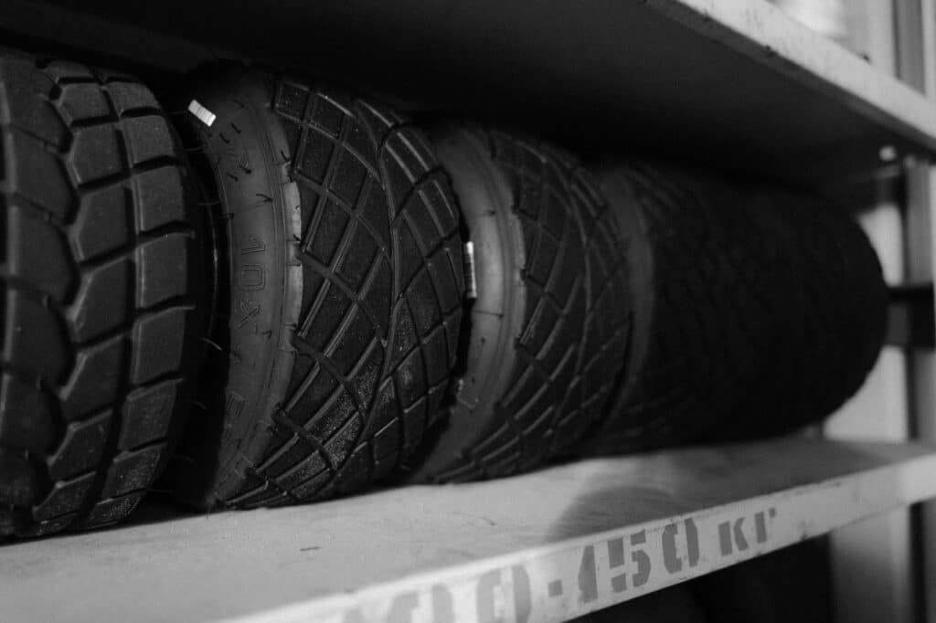 Monochrome photo of multiple tires arranged neatly on a shelf in a close-up shot.