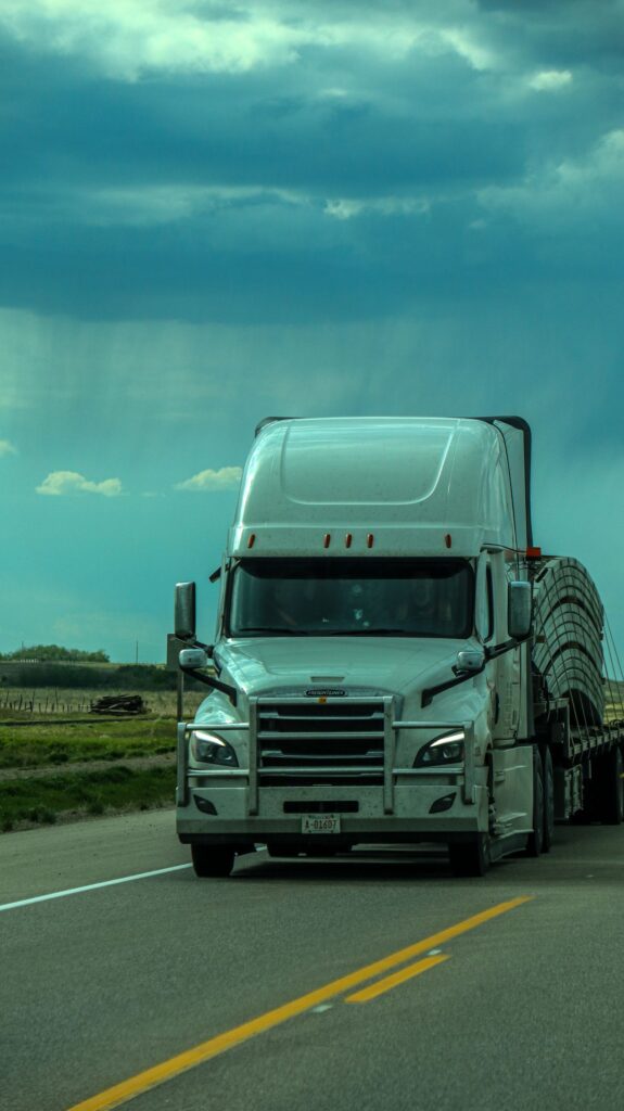 7 Considerations for Managing Commercial Truck Maintenance 1 A white semi-truck travels on a highway under a cloudy, dramatic sky.